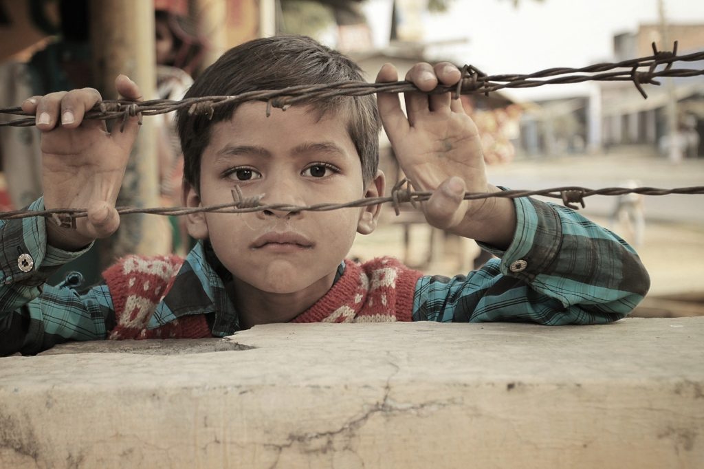 Indian child in poverty looking through barbed wire
