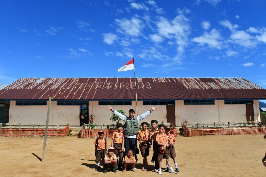 Teacher and students outside of a school